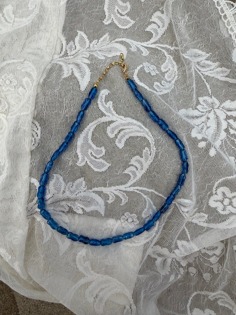 Blue beaded necklace on a white lace fabric background