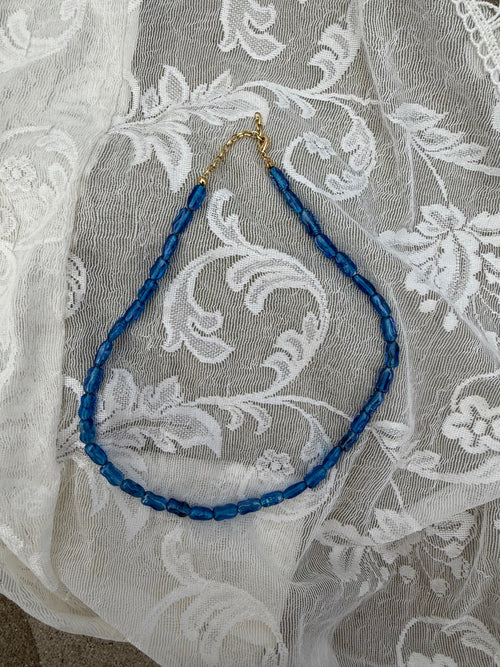 Blue beaded necklace on a white lace fabric background