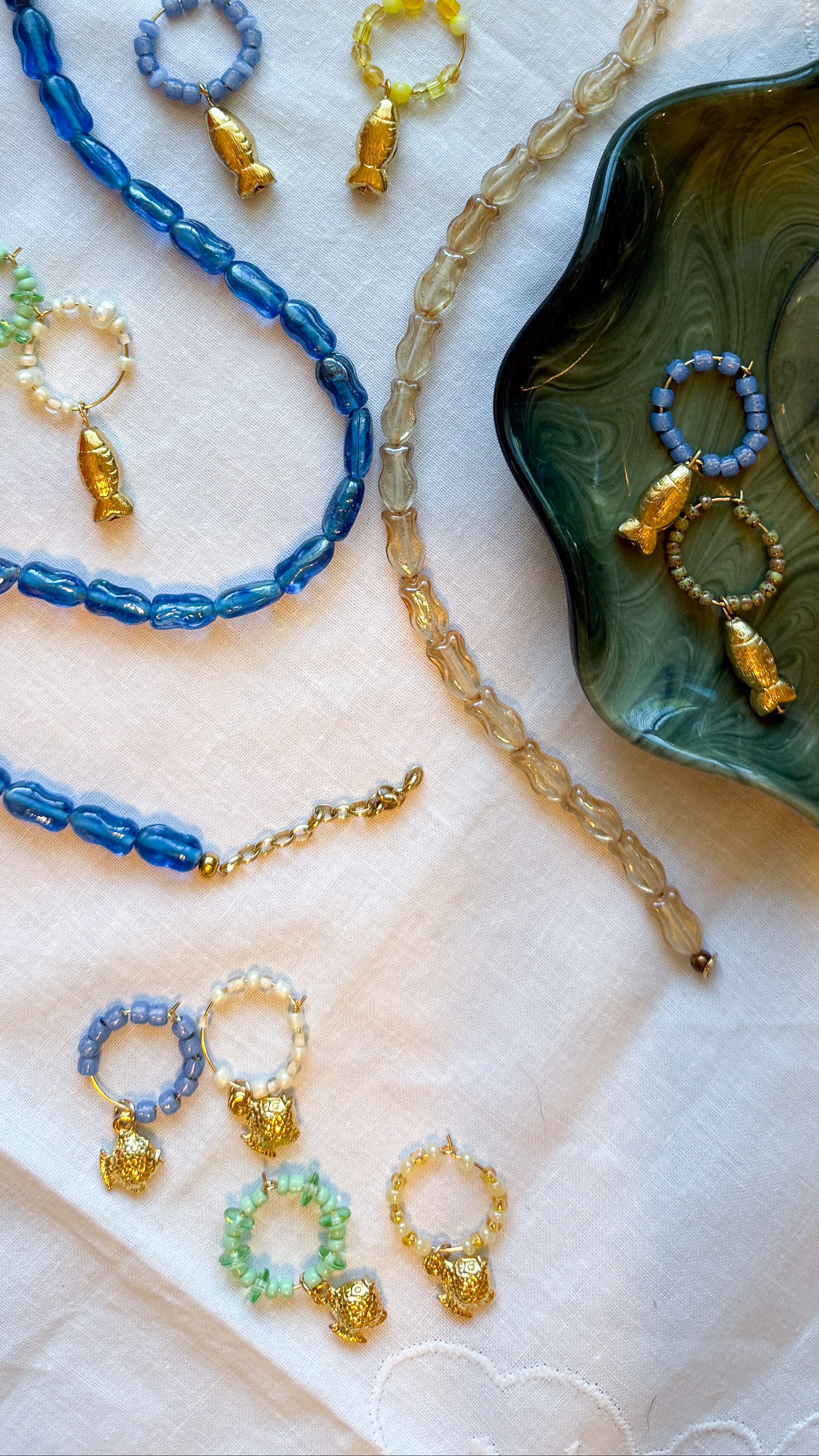 Jewelry set with blue and gold necklaces and earrings on a decorative surface.