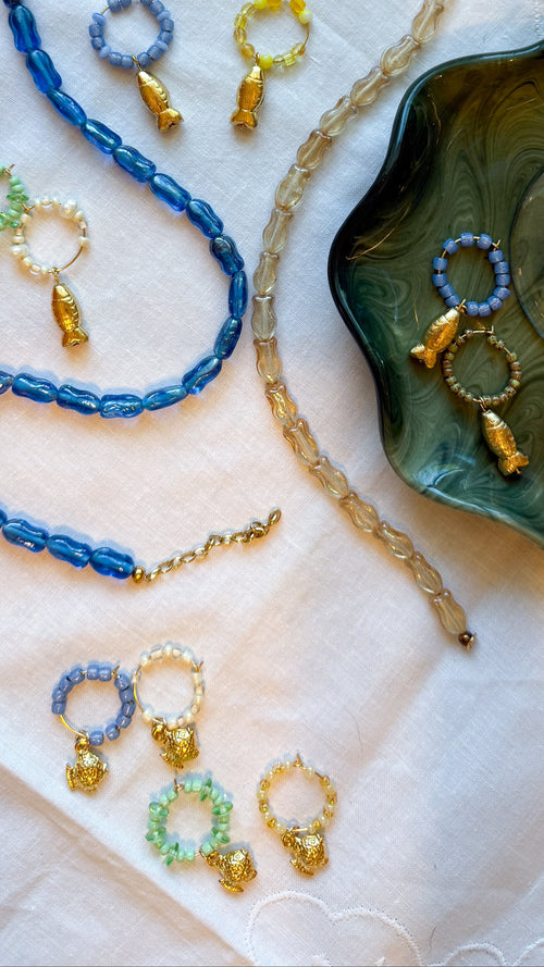 Jewelry set with blue and gold necklaces and earrings on a decorative surface.